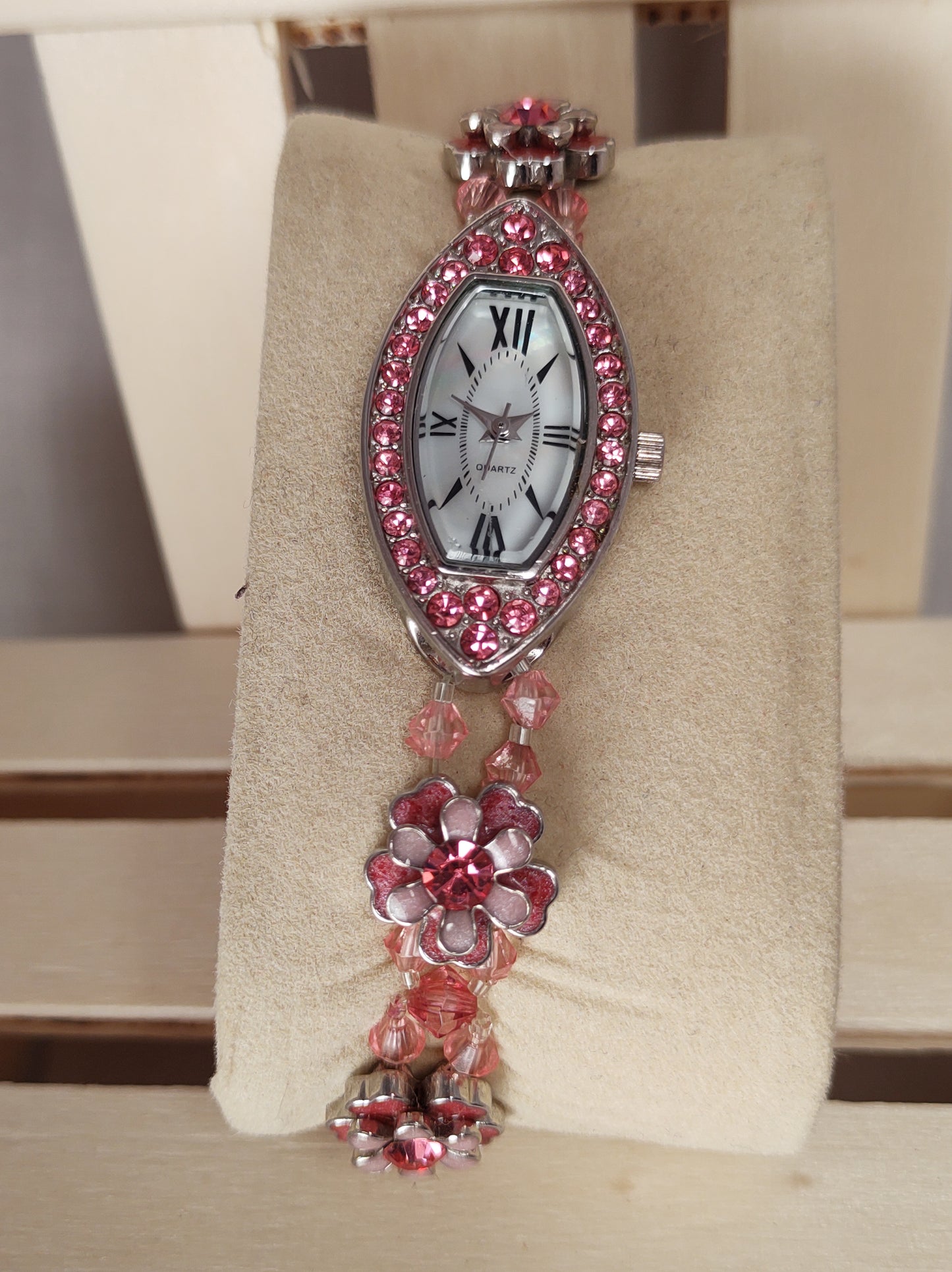 Simple brand pre-owned oval shaped watch surrounded by very nice imitation pink diamonds .. elastic band with flowers and a stainless clasp..light pink dial..Nice spring summer watch..