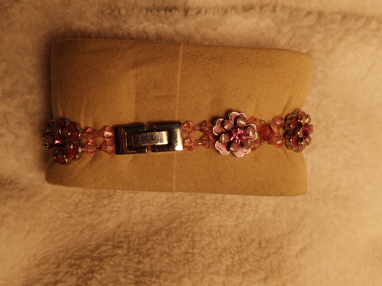 Simple brand pre-owned oval shaped watch surrounded by very nice imitation pink diamonds .. elastic band with flowers and a stainless clasp..light pink dial..Nice spring summer watch..